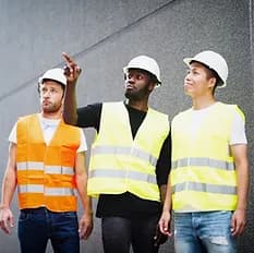 three construction workers standing pointing off screen